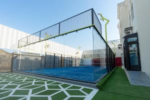 una pista de tenis en un recinto de cristal en un edificio en La Maison Resort en Doha