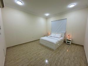 Habitación blanca con cama y mesa en La Maison Resort en Doha