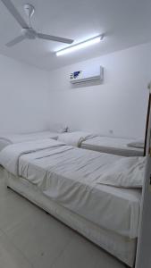a white bed with a ceiling fan in a room at Discovery Camp Bidiya in Badīyah