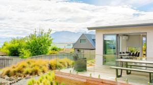 a house with a deck with a bench and a table at Two Fantails - Lake Views in Lake Tekapo