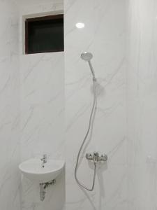 baño blanco con ducha y lavamanos en Hotel Andita Syariah en Surabaya