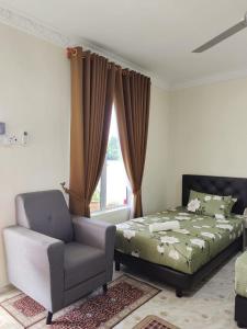 a bedroom with a bed and a chair and a window at Heal Inn Roomstay - Islam Guest in Kangar