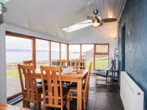 a dining room with a table and chairs and the ocean at Jubilee Cottage in Uig