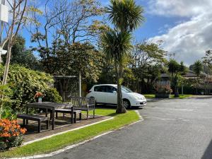 a white car parked in a parking lot with a table and benches at Summer Inn Motel in Orewa