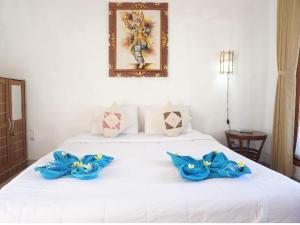 ペニダ島にあるWani Bali Bungalowのベッドルーム1室(青い弓が付いた白いベッド1台付)
