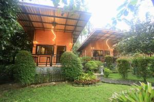 een houten huis met een hek en een tuin bij ปลายน้ำรีสอร์ท พรหมคีรี นครศรี ฯ Plainam Resort in Ban Khaek