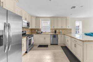 una cocina con armarios blancos y electrodomésticos de acero inoxidable en Cozy 3BR Newark Apt with Easy Access to NYC and Seton Hall, en Newark
