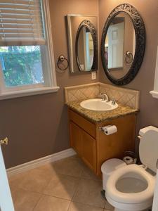 a bathroom with a toilet and a sink and mirrors at Casita in Ladera Ranch