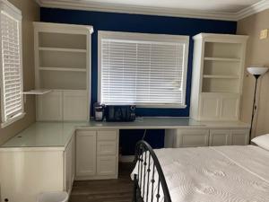 a bedroom with a bed and a desk and two windows at Casita in Ladera Ranch