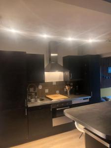 a kitchen with black cabinets and a sink at F3 avec jardin et piscine in Montpellier