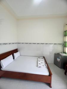 Cama en habitación con pared blanca en Motel Tiến Phúc, en Long Hai