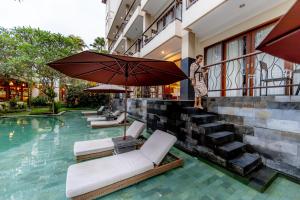 Anumana Ubud Hotel في أوبود: شخص واقف بجانب مسبح وفيه مظله