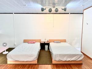 two beds in a room with white walls at 神津島民宿菊乃屋～きくのや～kikunoya in Kōzushima