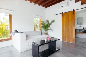 a living room with a white couch and a black table at HOLA villas & lofts Uluwatu in Uluwatu