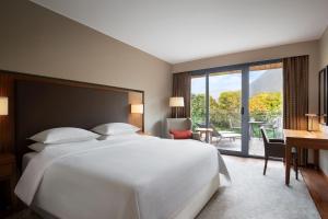una camera con un grande letto bianco e una scrivania con sedia di Sheraton Lake Como Hotel a Como