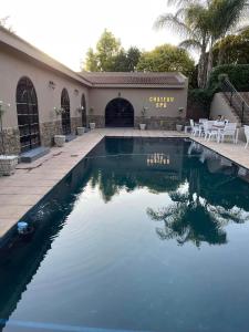 a swimming pool in front of a house at Château La Mer Exclusive Guesthouse & Spa in Hartbeespoort