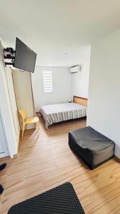 a room with a bed and a chair and a tv at Bungalow Soleil Sainte-Anne - Plage à pied in Sainte-Anne