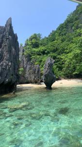 a beach with a rock formation in the water at Anang Balay Turista in El Nido