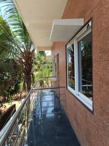 a balcony of a building with a window and a palm tree at Sunlight beach Homestay in Gokarn