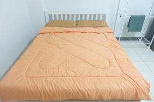 - un lit avec une couette en orange dans l'établissement ขนิษฐา อพาร์เม้น, à Thung Si Kan