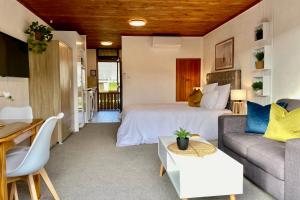 a bedroom with a bed and a couch and a table at The Swiss Chalet Holiday Apartment 4, Bay of Islands in Paihia