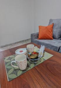 a coffee table with three cups and a tray of snacks at Cozy Homestays Meru in Meru