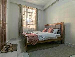 a bedroom with a bed and a window and shoes at Cozy Homestays Meru in Meru