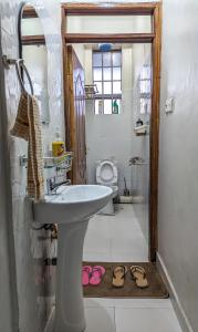 a bathroom with a sink and a toilet and a pair of slippers at Cozy Homestays Meru in Meru