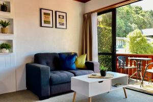 - un salon avec un canapé bleu et une table dans l'établissement The Swiss Chalet Holiday Apartment 6, Bay of Islands, à Paihia