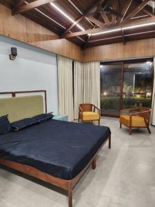 1 dormitorio con 1 cama y 2 sillas en Shantramniy 4bhk the Villa, en Bhuj