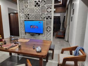 sala de estar con mesa y TV en la pared en Shantramniy 4bhk the Villa, en Bhuj