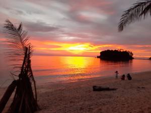 a person standing on a beach at sunset at Olivers Binucot Beach House in Romblon