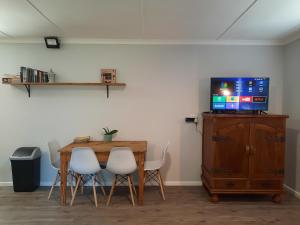 a dining room with a table and a tv on a cabinet at 23 Belladonna Cottage in Hermanus