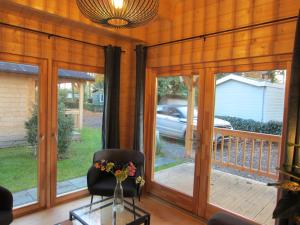 a room with sliding glass doors and a chair with flowers on a table at HderH - Eco Lodge op vakantiepark De IJsvogel, zwembaden, kids fun, natuur en rust in Voorthuizen