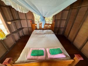 Bett in einem Zimmer mit zwei grünen und rosa Handtüchern in der Unterkunft Changthong Bungalow in Koh Chang Ranong