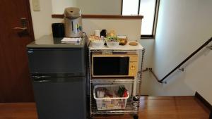 a small kitchen with a microwave and a refrigerator at Guest house Kotone KYOTO in Kyoto