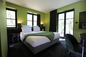 a bedroom with a bed with green walls and windows at Hôtel-SPA Le Moulin De La Wantzenau - Strasbourg Nord in La Wantzenau