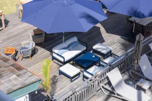 - une vue sur la terrasse pourvue de chaises et d'un parasol dans l'établissement Hotel Le Boucan Canot, à Saint-Gilles les Bains