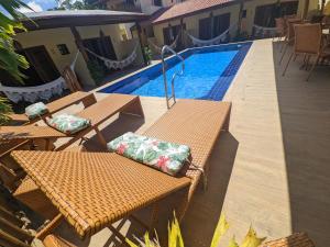 a swimming pool with two tables and chairs next to a swimming pool at Pousada Lua Nova Pipa Chales com Hidromassagem e Jacuzzi in Pipa