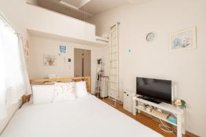a bedroom with a bed and a flat screen tv at ROOMS Ropponmatsu02 in Fukuoka