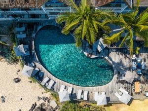 an overhead view of a swimming pool with chairs and palm trees at Hotel Le Boucan Canot in Saint-Gilles les Bains