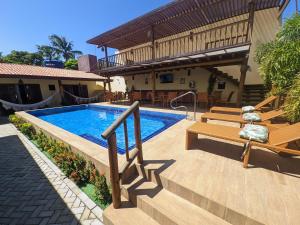 una piscina con bancos junto a una casa en Pousada Lua Nova Pipa Chales com Hidromassagem e Jacuzzi, en Pipa