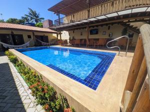 - une piscine avec du carrelage bleu sur le côté d'une maison dans l'établissement Pousada Lua Nova Pipa Chales com Hidromassagem e Jacuzzi, à Pipa