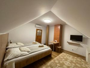 a bedroom with a large bed and a tv at Penzion Dori in Diakovce