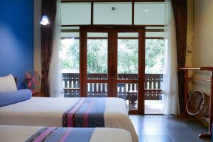a bedroom with two beds and a large window at AuangKham Resort in Lampang