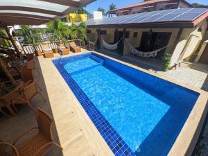 - une vue sur la piscine avec des chaises et une maison dans l'établissement Pousada Lua Nova Pipa Chales com Hidromassagem e Jacuzzi, à Pipa