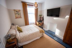 a bedroom with a bed and a flat screen tv at 4-bed botanical retreat in Plymouth