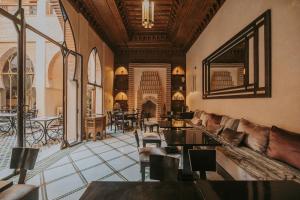 uma sala de estar com um sofá, mesas e cadeiras em Riad Le Perroquet Bleu Suites & Spa em Marrakech