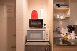 a microwave oven with a red container on top of it at ROOMS Ropponmatsu02 in Fukuoka