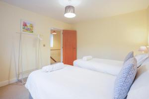 two beds in a room with white sheets at Staddlestone Mews in Broadway